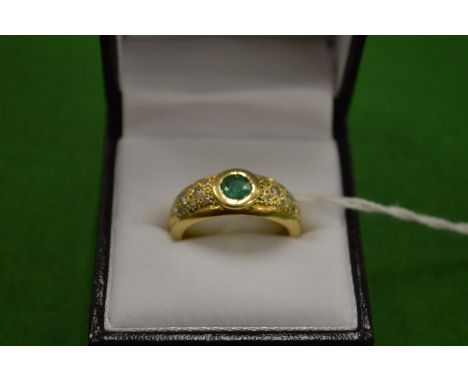 An 18ct gold ring set with a single central emerald flanked by diamonds to the shoulders size Q.