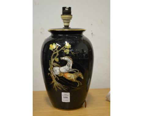 A pottery table lamp decorated with horses.