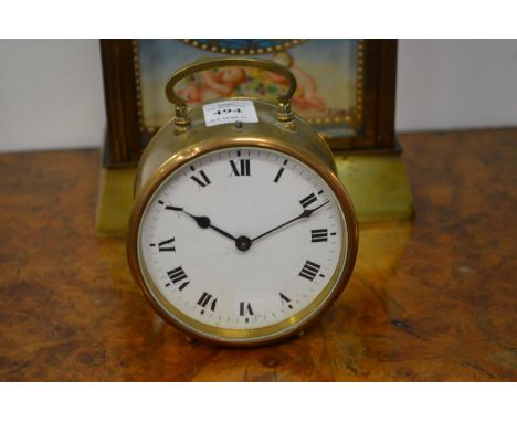 A small brass circular bedside clock with enamel dial.