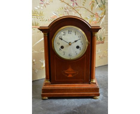 An Edwardian inlaid mahogany mantle clock with column supports to the case.