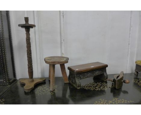 A 17th Century Gothic style carved oak stool, an elm primitive stool, fruitwood clamp and a carved wood lamp 