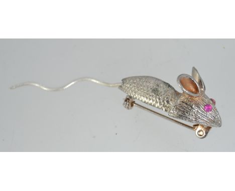 A vintage white metal mouse pin brooch with pink paste set eyes and articulated tail having a roller clip clasp. Measures 7cm
