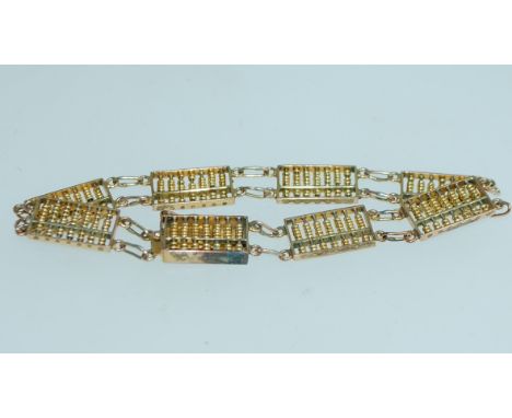 A yellow metal Hong Kong abacus bracelet with clip clasp. Marked 14 K. Likely plated. Measures 7.5 inches.