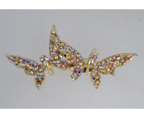 A vintage yellow metal brooch in the form of two butterflys with Aurora Borealis rhinestone set bodies and roller clip clasp.