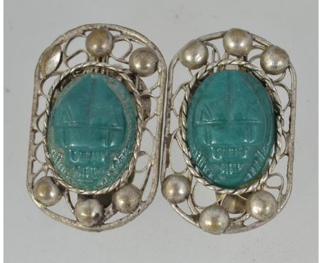 A pair of vintage white metal clip on earrings with carved jade style resin scarabs in a filigree setting. Measures 2. 5cms.