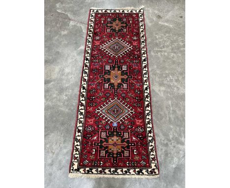 A Persian Karadja red ground carpet runner. 66' x 26'