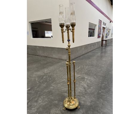 A 19th century brass telescopic candle lamp standard with three lights each with a glass chimney, on a triple column support 