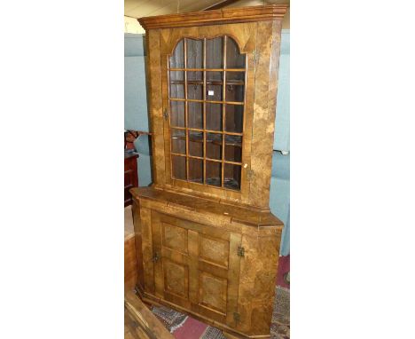 An early Georgian style burr figured and crossbanded walnut freestanding corner cabinet, having glazed upper door with fixed 