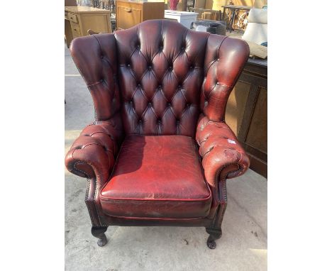 AN OXBLOOD WINGED BUTTON BACK FIRESIDE CHAIR ON CABRIOLE LEGS 