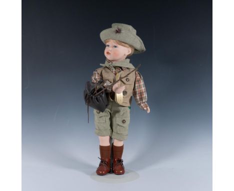 This hand-painted doll, with delicate legs and arms made from fine bone porcelain, is dressed for a charming camping and fish