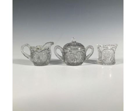 A set of three clear glass items, a creamer, sugar jar, and toothpick holder, all decorated with sun patterns and delicate ab