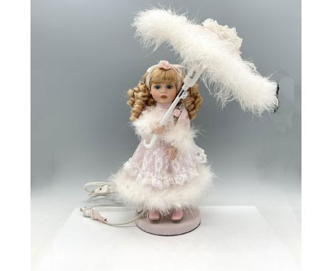 Hand painted porcelain doll dressed in pink with lace overdress carrying a pink feathered parasol. Twist switch on cord. Issu