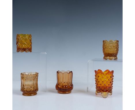 A charming set of six amber colored toothpick holders that features two hobnail footed pieces, one designed in an eight sided