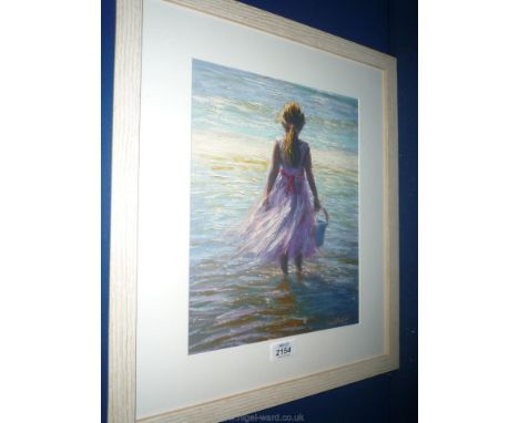 A framed Print of a young girl stood in the sea with a bucket; signed lower right 'Steff'.