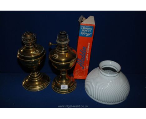 Two brass oil lamp bases, boxed chimney and an opaque shade.