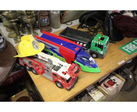 A child's toy fire engine; fire chief plastic helmet; a futuristic car transporter and a Man lorry 