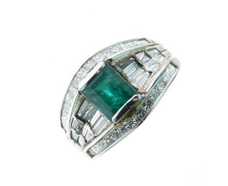 Emerald and diamond dress ring, the white mount stamped '18k', the step cut stone between baguette cut shoulders, and a line 