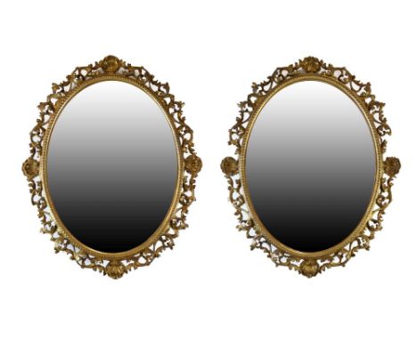 Pair of 19th Century giltwood and gesso oval wall mirrors, each having a plain plate with beaded surround and pierced foliate