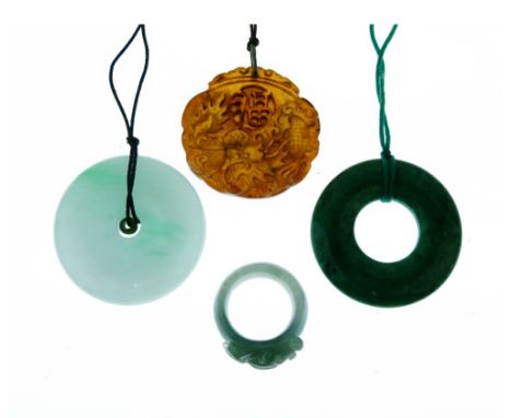Circular jade pendant, on cord; another similar; a jade ring carved with a fish; and a brown jade carved pendant on a cord   