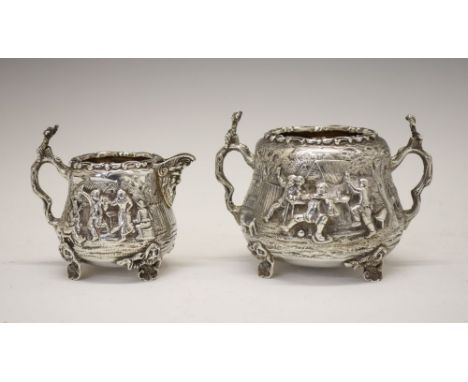 Edward VII silver milk jug and sugar basin, having allover decoration of a tavern exterior scene, with naturalistic handles a