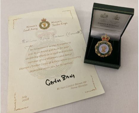 A boxed Women's Land Army And Timber Corps award badge with presentation certificate.  Presented to Rosina Jean James (Powell