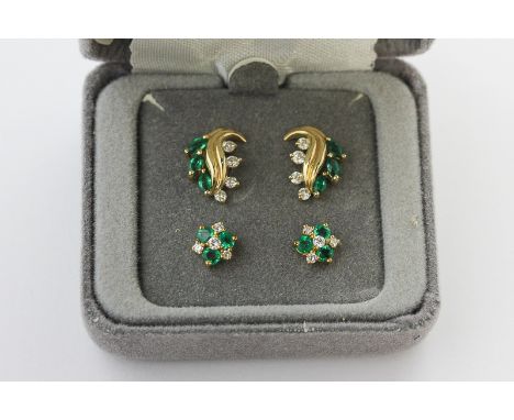 A pair of emerald and diamond cluster ear studs on post and butterfly fittings, and a pair of emerald and diamond leaf scroll