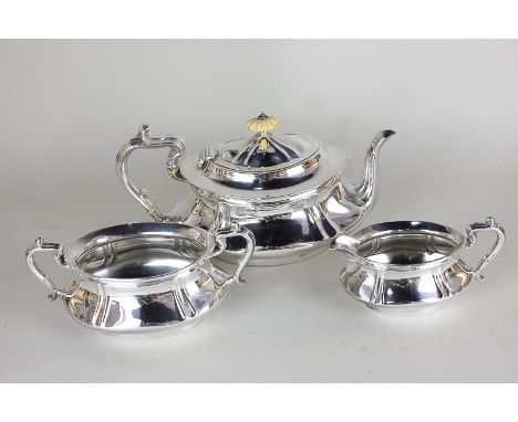 A George V silver three piece tea set of teapot, sugar bowl and cream jug, oval shape with scroll handles, maker William Henr