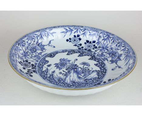 A Japanese porcelain blue and white dish decorated with a border of bamboo and flowers surrounding circular panel of tree tru