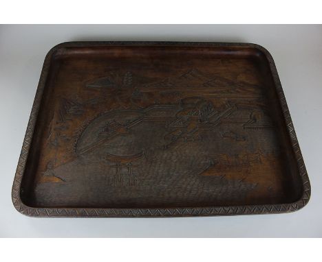 A Japanese carved wood tray, of shaped rectangular form, decorated with a landscape view across a port with distant small bui