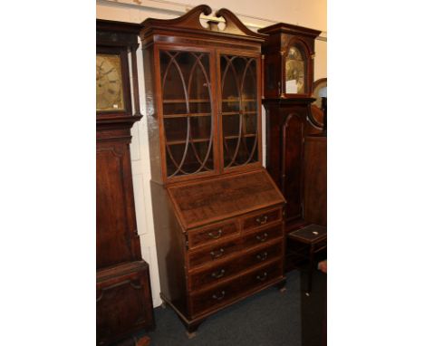 An Edwardian inlaid mahogany George III style bureau bookcase with swan neck arch cornice, oval panel glazed doors enclosing 