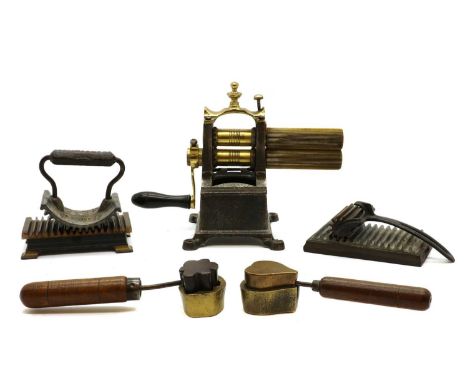 A collection of crimping irons and tools, 19th century, comprising a brass and cast iron crimping machine, 29cm wide, a Genev