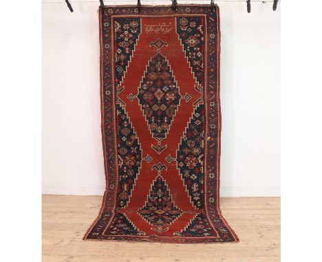 A Kazak carpet,with two navy medallions, to a red field and navy floral borders, signed and dated, 312 x 130cmCondition Repor