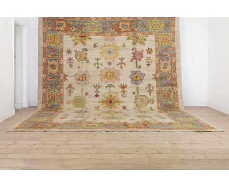 An Oushak wool carpet,of recent manufacture, Turkish (West Anatolian), woven with stylised floral motifs to a pale ground,402