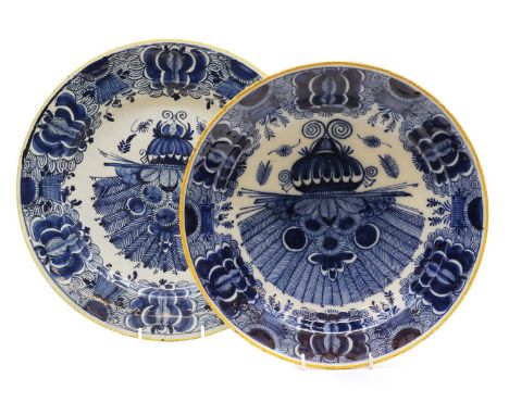 A Dutch Delft blue and white charger and bowl,each decorated with a central urn of flowers within foliate borders and yellow 