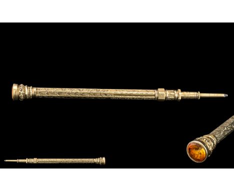 A Yellow Metal Propelling Pencil, engraved decoration, with a faceted citrine coloured terminal.