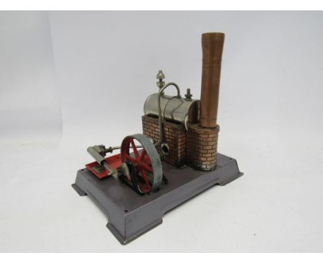 A German live steam stationary engine, probably by Wilesco, the horizontal boiler raised on a copper brickwork effect plinth 