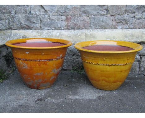 A pair of vintage ochre glazed planters of circular tapered form with flared rims, press moulded bands and further detail, 54