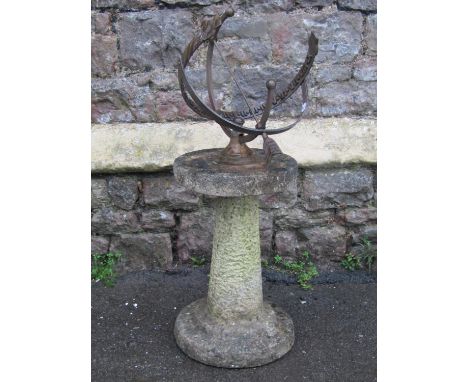 A vintage cast metal armillary sundial mounted on a two sectional weathered cast composition stone pedestal with circular bas