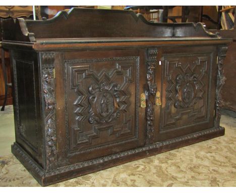 A substantial 19th century oak side cupboard enclosed by a pair of panelled doors, oval portrait panels, flanked by pilasters