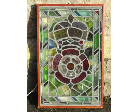 A rectangular stained glass panel with rose and crown detail, framed in a light box 71 cm x 45 cm (overall size) 