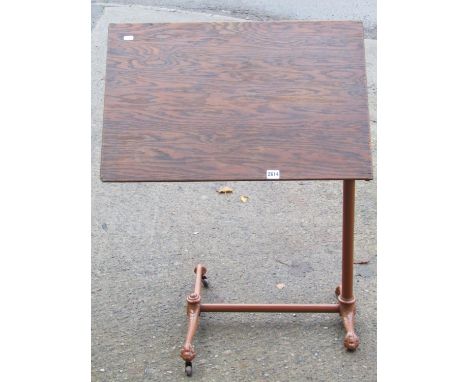 A Victorian cast iron cantilever bed table with adjustable framework and timber top, the feet with scale and claw and ball su