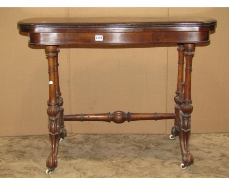 A walnut and figured walnut veneered fold over top card table with serpentine outline, raised on turned and scrolled supports