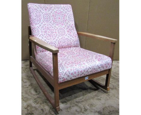 A vintage mid 20th century low oak framed rocking chair with combined upholstered seat and back 