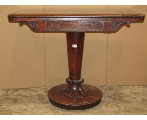 A 19th century rosewood foldover top tea table with scrolled frieze raised on a simple turned tapered pillar, petal collar an