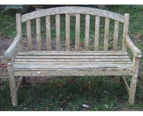 A weathered botanic teak garden bench with slatted seat and back beneath an arched rail, 4ft wide, together with an accompany