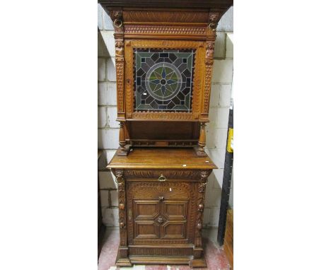 A 19th century oak pier cabinet, the lower section enclosed by a quarter panelled door and frieze drawer flanked by carved fr