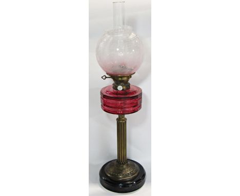 A J &amp; S Lee &amp; Sons Hinks patent oil lamp with a cranberry glass reservoir supported by a brass column, faded pink flo