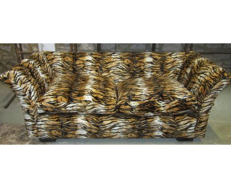 A two seat sofa with swept arms upholstered in a tiger print fabric with loose squab feather filled seat cushions 195 cm wide