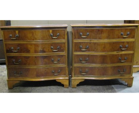 A pair of reproduction Georgian style yew wood veneered four drawer serpentine front chests of drawers raised on bracket feet