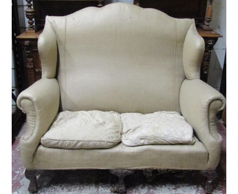 A good quality Edwardian two seat sofa frame with shaped outline, winged borders and scrolled arms raised on carved mahogany 